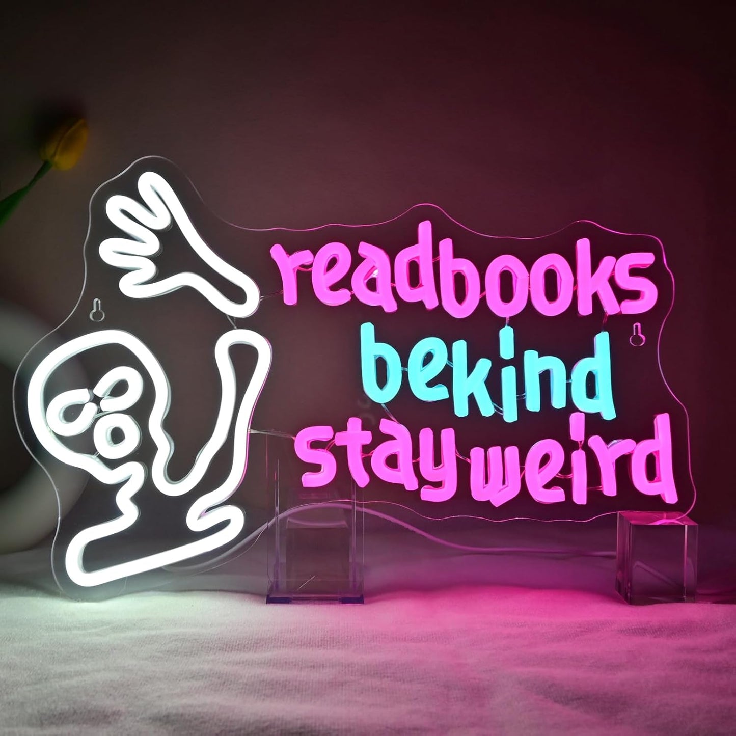 Waving alien neon sign with the phrase "Read Books Be Kind Stay Weird" glowing in LED lights