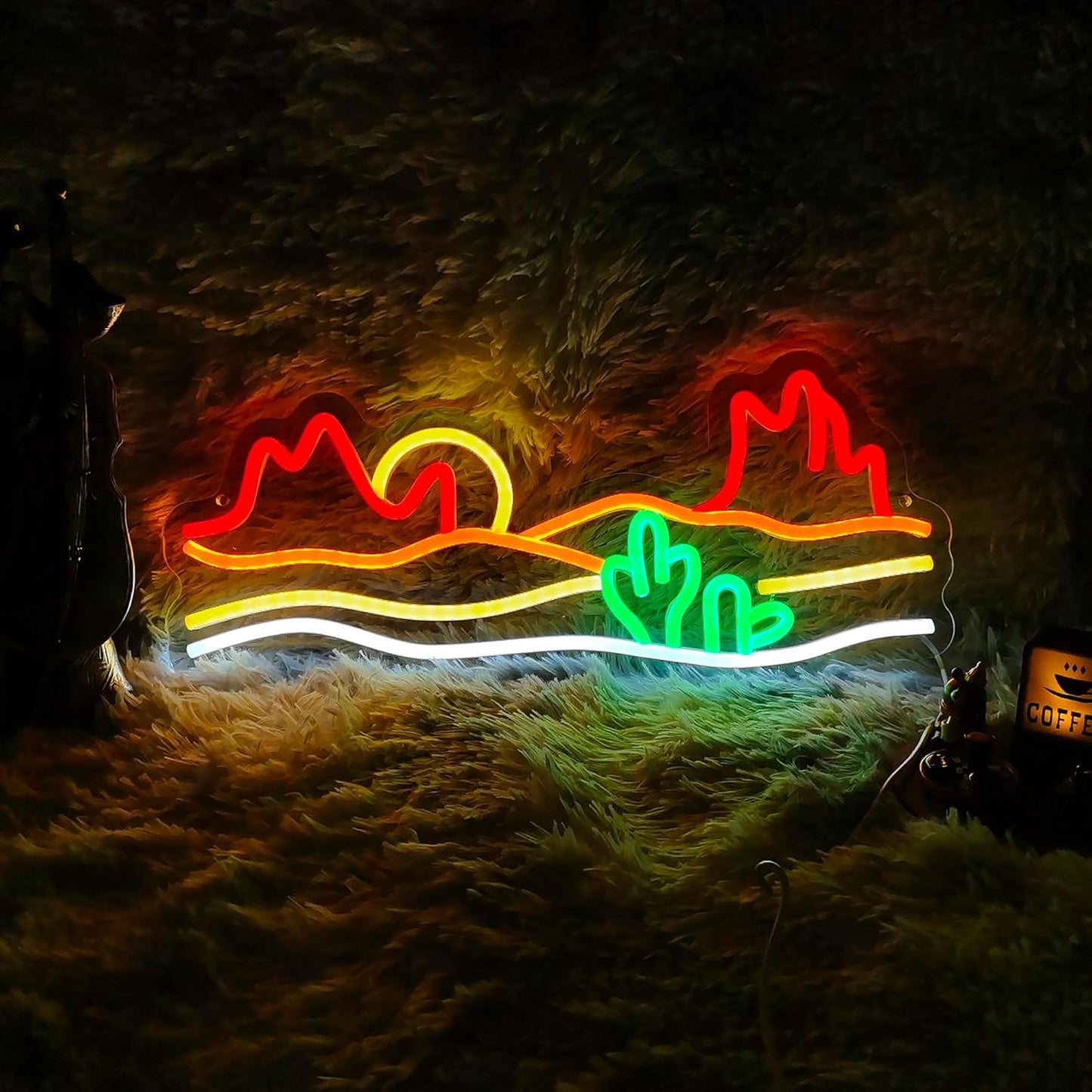 Neon sign of a desert sunset with cacti and mountains