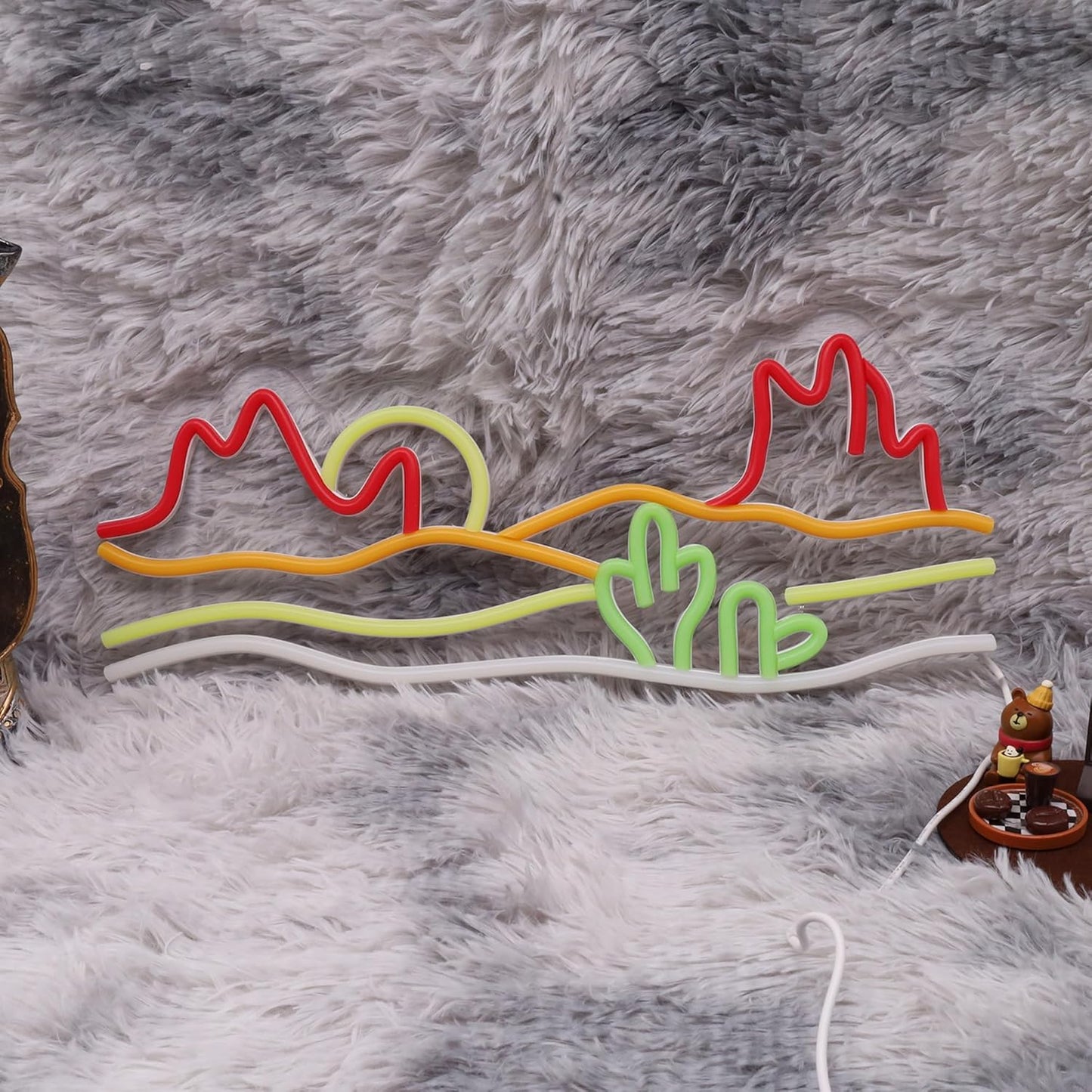 Neon sign of a desert sunset with cacti and mountains