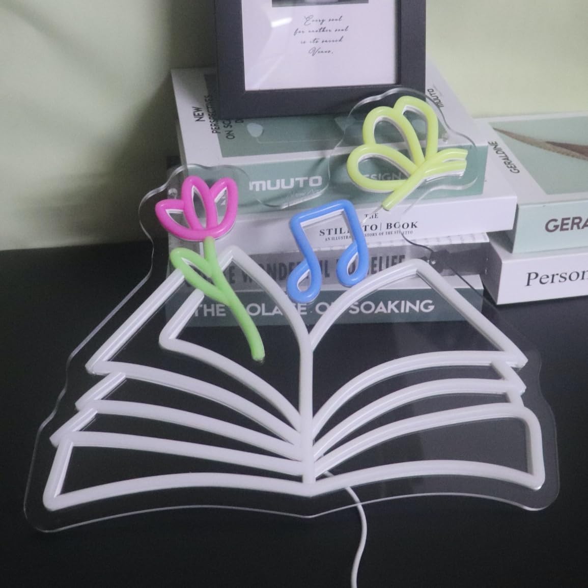 Neon sign of a magical book with glowing butterflies, flowers, and musical notes