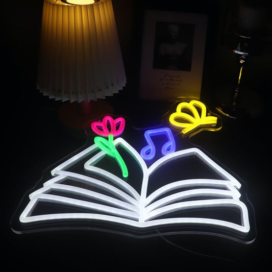 Neon sign of a magical book with glowing butterflies, flowers, and musical notes